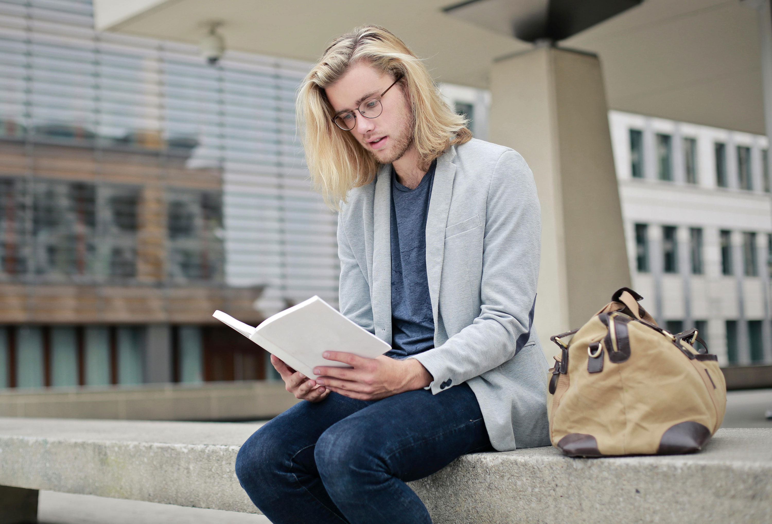 Graduate student reviewing study materials on campus steps preparing for GMAT exam